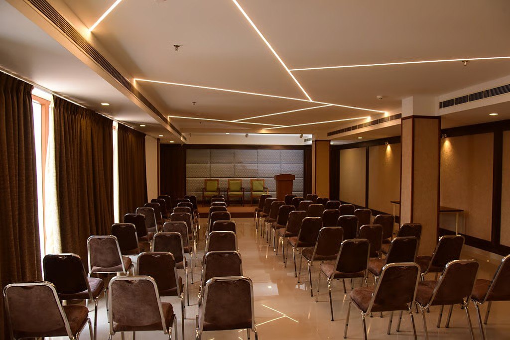 The conference hall set theatre-style, with a head table, a lectern and rows of upholstered chairs under lit ceiling lines